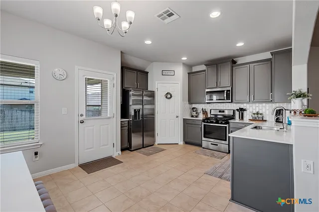 a large white kitchen with a refrigerator a stove top oven a sink dishwasher and white cabinets with wooden floor