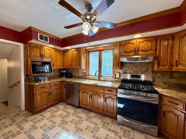 a kitchen with stainless steel appliances granite countertop a stove top oven a sink and cabinets