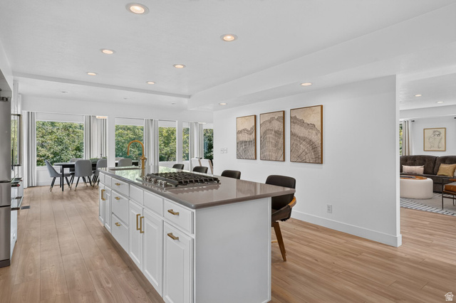 1979 Cave Hollow Way Bountiful, UT 84010 - Photo 14 of 59 Kitchen island with integrated gas cooktop, light-toned wood-finish flooring, recessed lighting, and white cabinetry with brass hardware