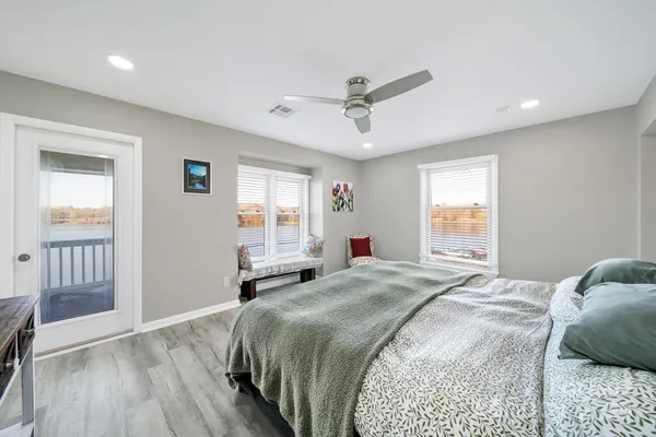 a spacious bedroom with a bed a dresser and wooden floor