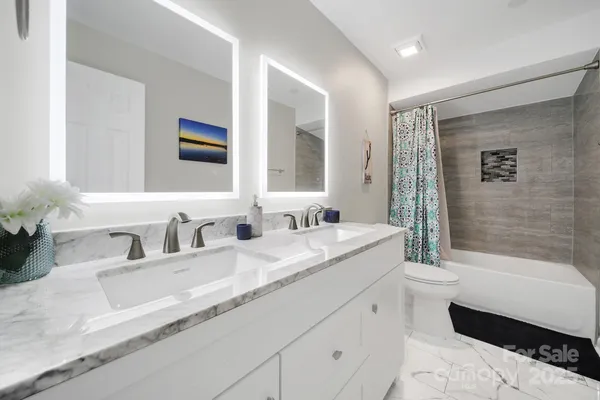 a bathroom with a granite countertop sink mirror and a bathtub