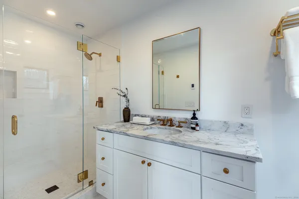 a bathroom with a granite countertop sink a mirror and shower