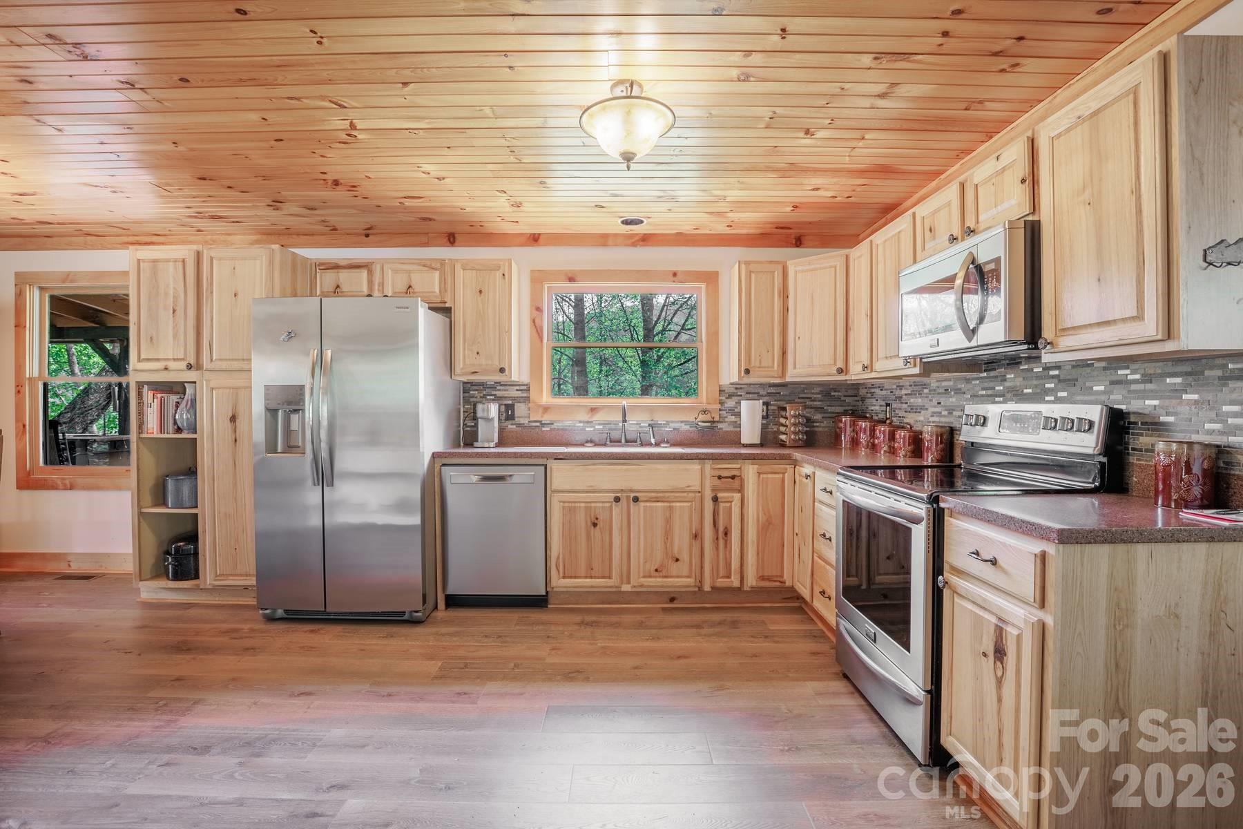 440 Huskey Road Bryson City, NC 28713 - Photo 7 of 42 a kitchen with stainless steel appliances granite countertop a stove a sink dishwasher a refrigerator and cabinets with wooden floor