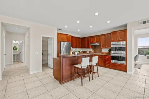 a kitchen with stainless steel appliances kitchen island granite countertop a refrigerator and cabinets
