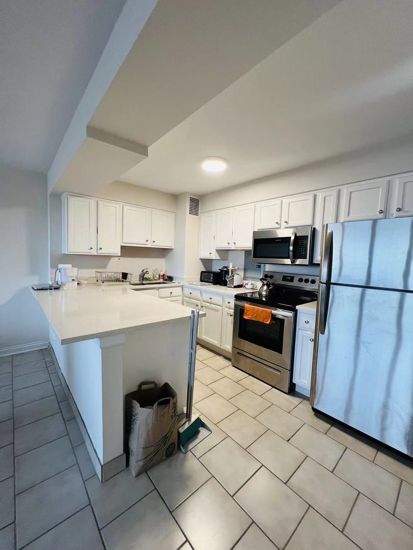 6030 North Sheridan Road, Unit 811 Chicago, IL 60660 - Photo 4 of 6 a kitchen with stainless steel appliances a stove a sink a microwave and a refrigerator