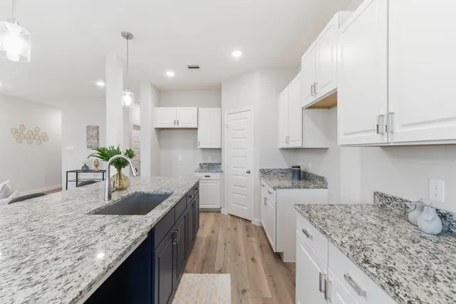 a kitchen with kitchen island granite countertop a sink a counter top space and cabinets