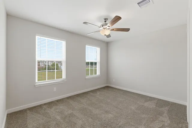 an empty room with windows and fan