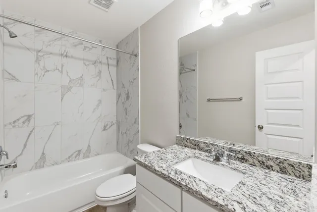 a bathroom with a granite countertop sink a toilet and shower
