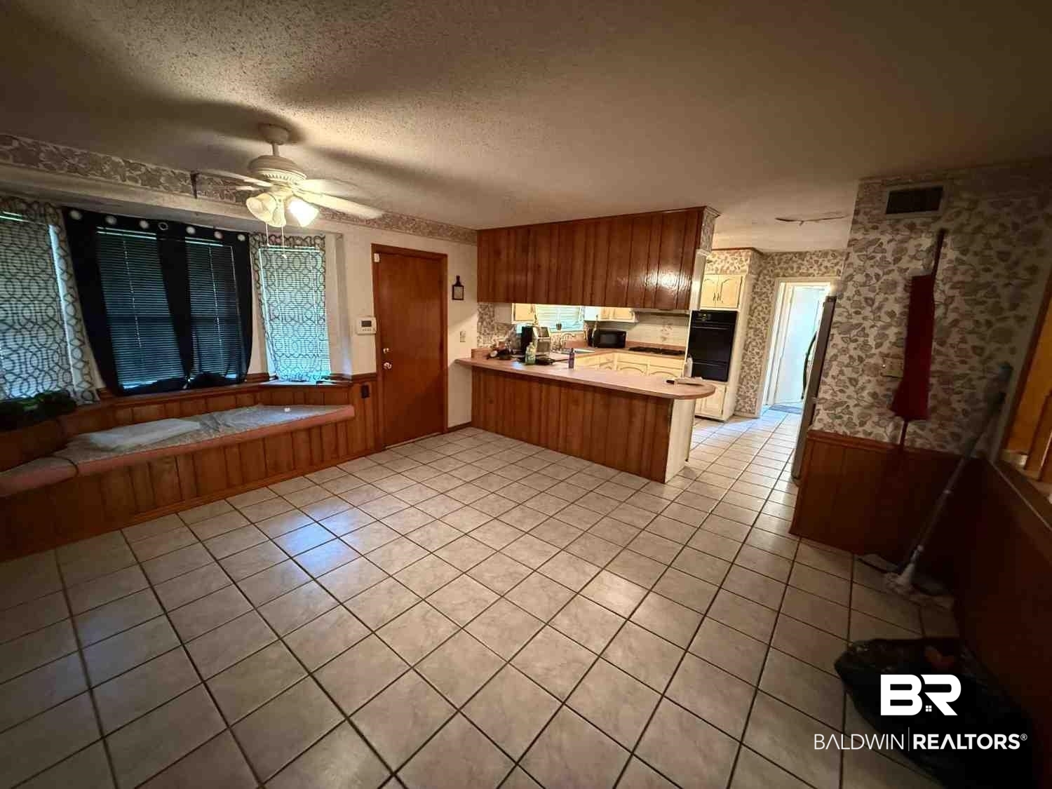3721 Robertson Court Mobile, AL 36693 - Photo 8 of 22 Kitchen with wallpapered walls, a wainscoted wall, light countertops, a peninsula, and a textured ceiling