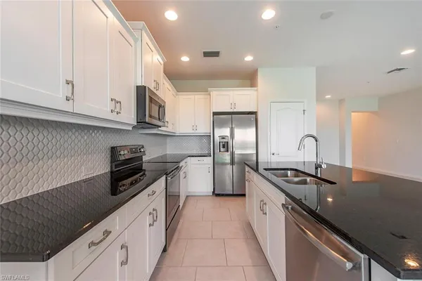 a kitchen with granite countertop a sink a stove and refrigerator