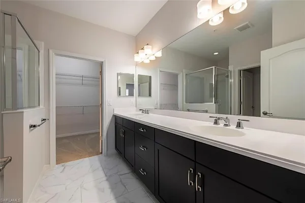 a bathroom with a double vanity sink a large mirror and a shower