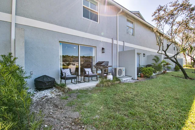 a view of a backyard with table and chairs potted plants and a large tree