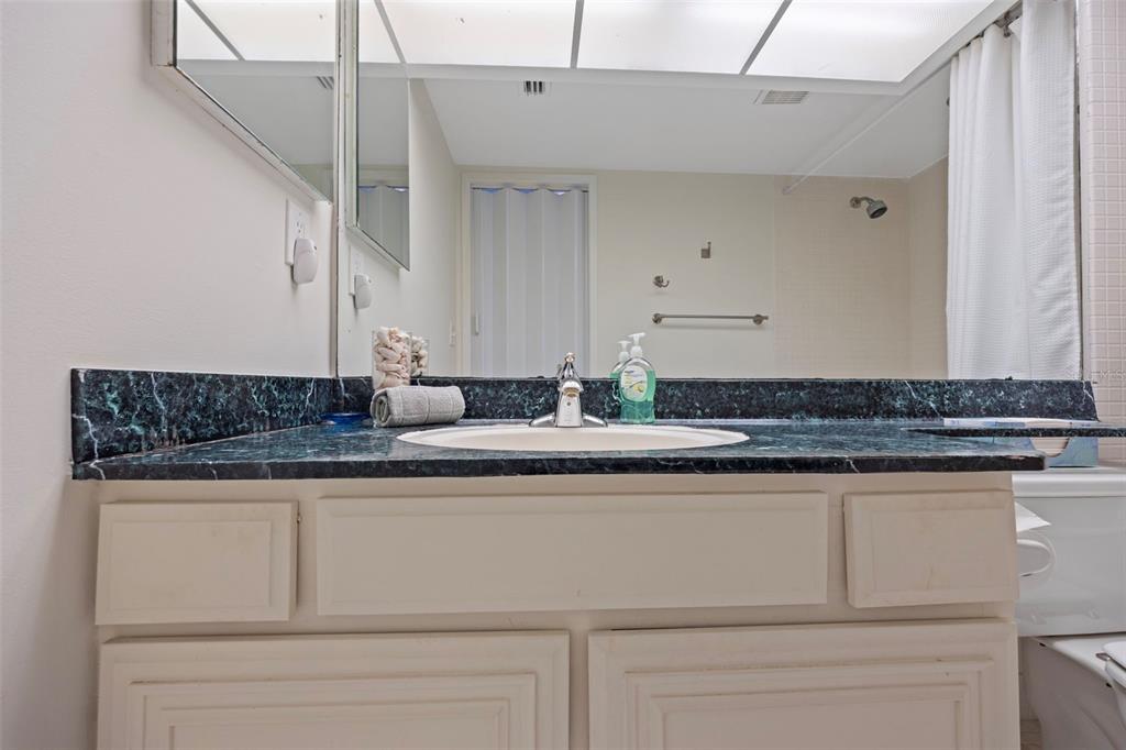 9425 Blind Pass Road, Unit 1006 St. Pete Beach, FL 33706 - Photo 22 of 45 a sink with granite countertop white cabinets and a granite counter top