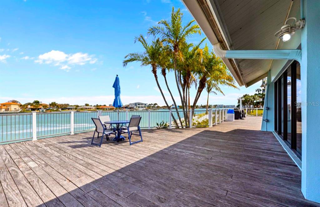 9425 Blind Pass Road, Unit 1006 St. Pete Beach, FL 33706 - Photo 38 of 45 a view of a terrace with wooden floor and outdoor seating