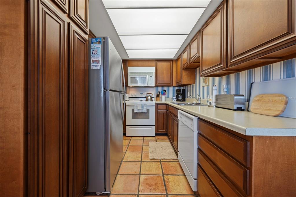 9425 Blind Pass Road, Unit 1006 St. Pete Beach, FL 33706 - Photo 9 of 45 a kitchen with stainless steel appliances granite countertop a refrigerator and a stove top oven