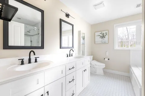 a bathroom with double vanity sink a mirror and a toilet