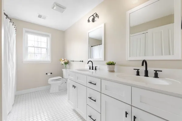 a bathroom with double sink a toilet and a window