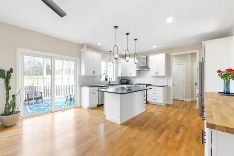 a large kitchen with granite countertop a large counter top a sink stainless steel appliances and cabinets