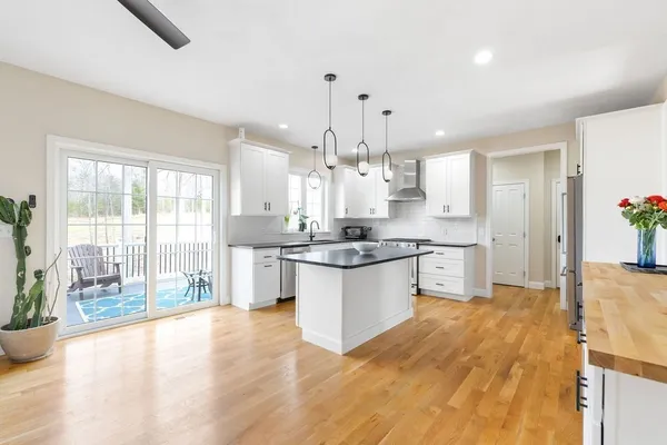 a large kitchen with granite countertop a large counter top a sink stainless steel appliances and cabinets