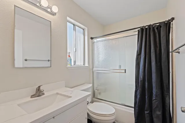 a bathroom with a sink a toilet a mirror and shower