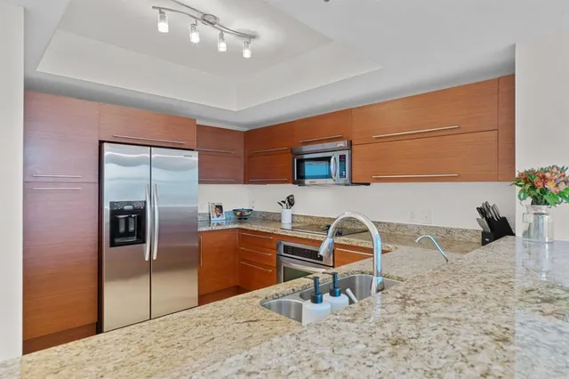 a kitchen with stainless steel appliances kitchen island granite countertop a refrigerator and a sink