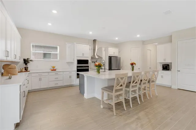 a kitchen with stainless steel appliances a white table chairs and a refrigerator
