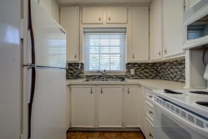2320 26th Street Lubbock, TX 79411 - Photo 5 of 17 a kitchen with a refrigerator and white cabinets
