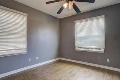 a view of an empty room with a window and wooden floor