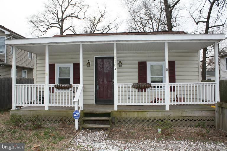 7830 A East Shore Road Pasadena, MD 21122 - Photo 2 of 6 a view of a house with a small yard and a large tree