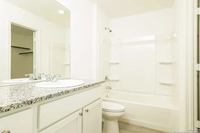 a bathroom with a granite countertop sink mirror vanity and toilet