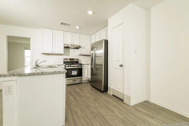 a kitchen with granite countertop white cabinets and stainless steel appliances