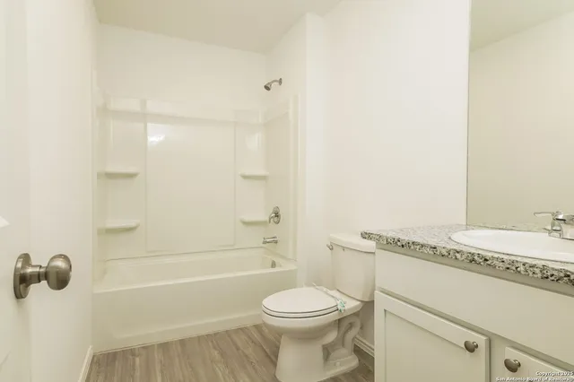 a bathroom with a granite countertop bathtub sink vanity mirror and toilet