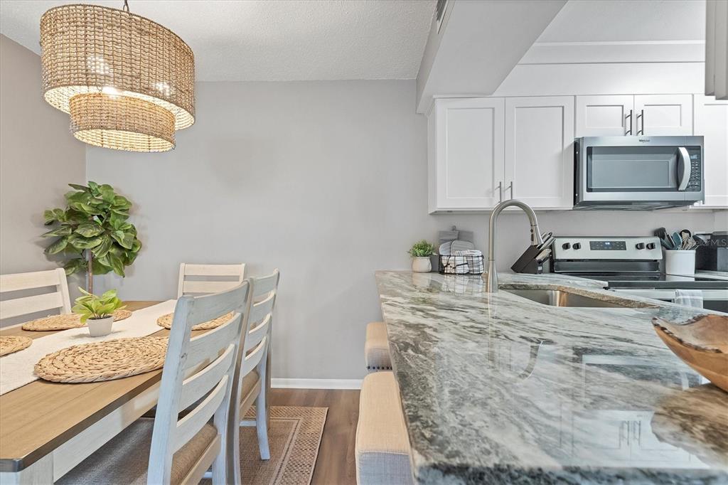 3239 South Beneva Road, Unit 101 Sarasota, FL 34232 - Photo 12 of 37 a kitchen with stainless steel appliances granite countertop a sink dishwasher a microwave oven a stove with wooden cabinets and floor