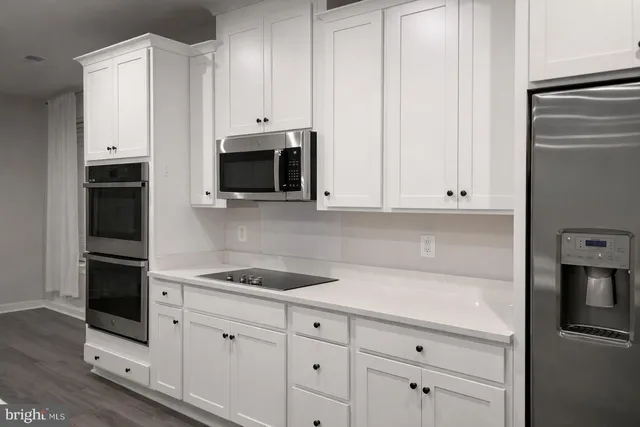 a kitchen with granite countertop white cabinets and stainless steel appliances