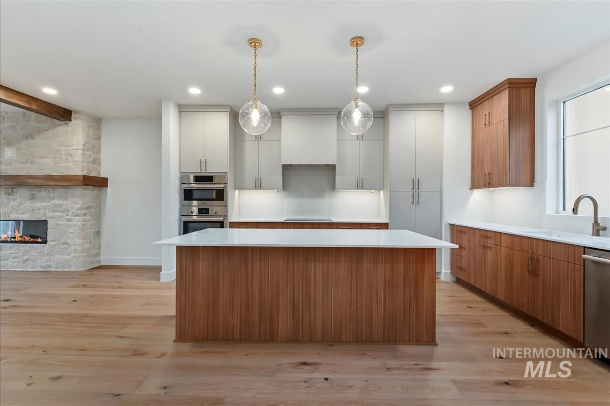 3213 West Moore Street Boise, ID 83702 - Photo 12 of 32 Kitchen featuring a large central island with a white countertop and wood-finish paneling, complemented by dual pendant lights