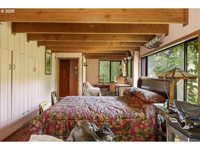 a bedroom with a bed and large windows