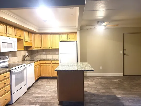 a large kitchen with granite countertop a sink window and cabinets