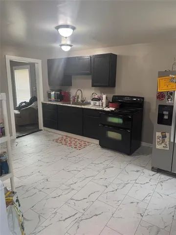 a kitchen with stainless steel appliances kitchen island granite countertop a refrigerator and a stove top oven