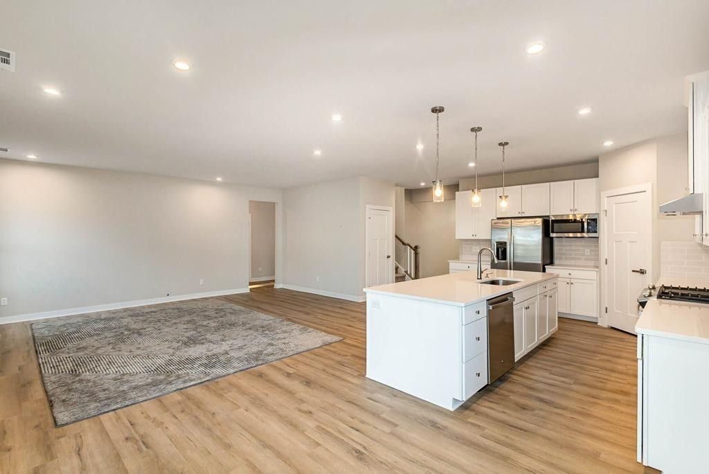 4003 Bluebell Lane Spring Hill, TN 37174 - Photo 5 of 40 a large kitchen with a stove a sink a refrigerator and white cabinets with wooden floor