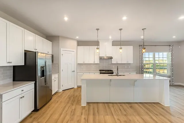 a large kitchen with stainless steel appliances kitchen island granite countertop a large counter top and a wooden floors