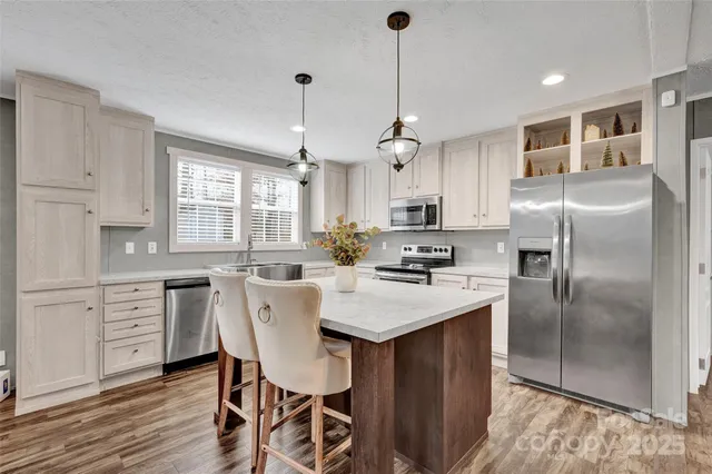 a kitchen with stainless steel appliances kitchen island granite countertop a table chairs refrigerator and sink