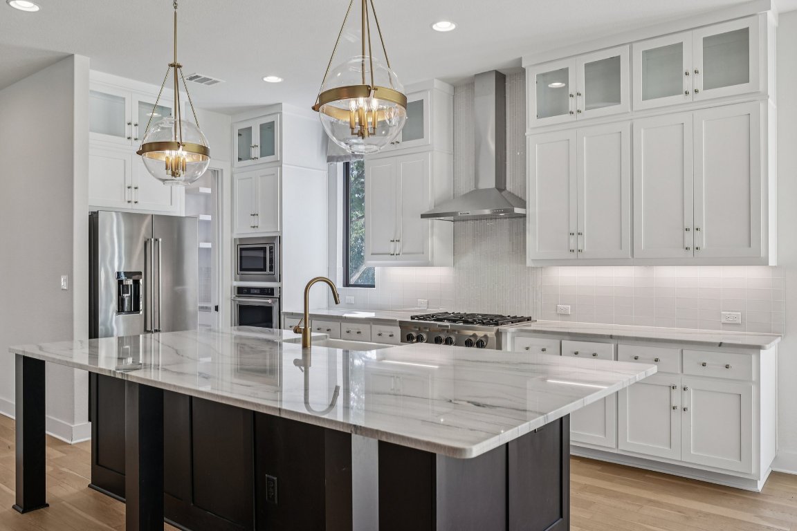 19316 Splendor Court Jonestown, TX 78645 - Photo 12 of 40 a kitchen with stainless steel appliances granite countertop a sink a stove and a refrigerator