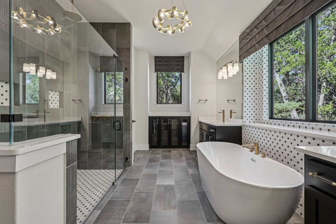 19316 Splendor Court Jonestown, TX 78645 - Photo 19 of 40 a spacious bathroom with a bathtub a sink and a large mirror