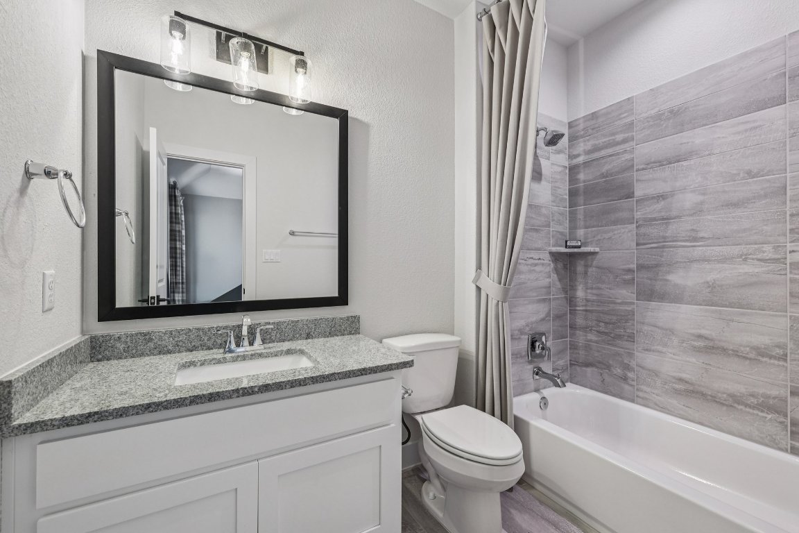 19316 Splendor Court Jonestown, TX 78645 - Photo 33 of 40 a bathroom with a granite countertop toilet a sink and a bathtub