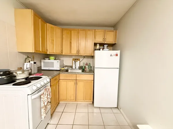 a kitchen with a refrigerator a stove top oven and cabinets