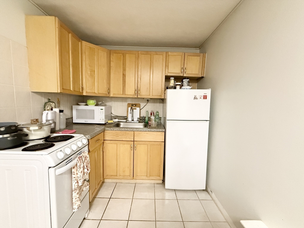 a kitchen with a refrigerator a stove top oven and cabinets