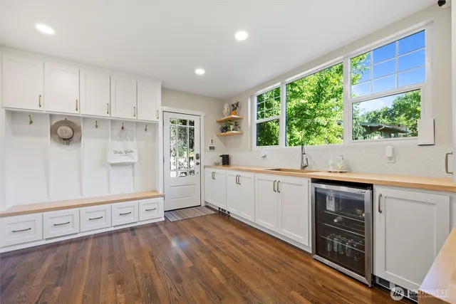 a kitchen with stainless steel appliances white cabinets a sink and wooden floor