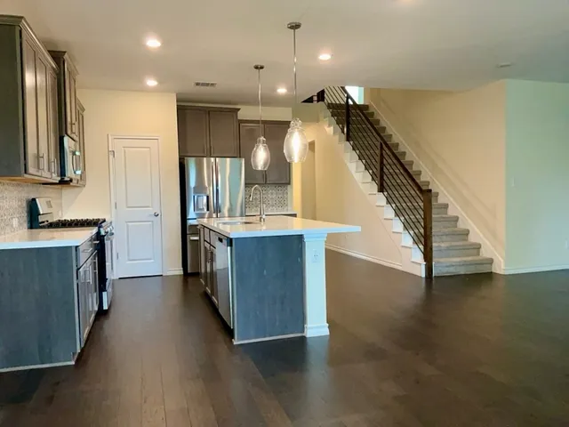 an empty room with wooden floor a ceiling fan and windows