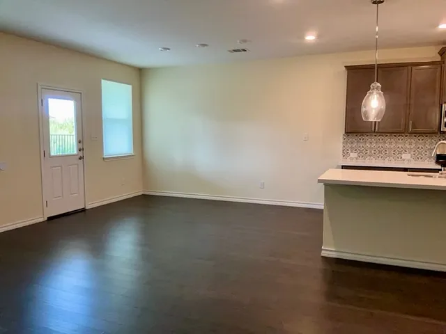 an empty room with wooden floor a ceiling fan and windows