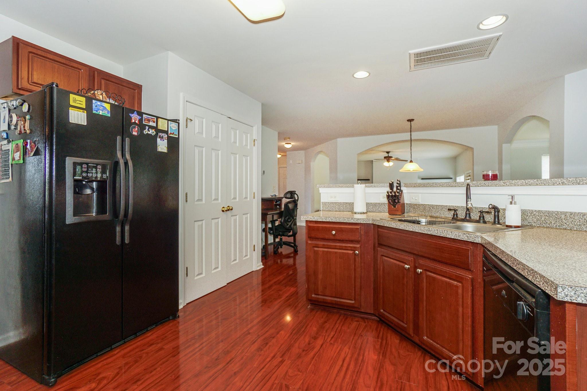 166 Glennallen Road Mooresville, NC 28115 - Photo 15 of 48 a kitchen with stainless steel appliances granite countertop a refrigerator a sink dishwasher and wooden cabinets with wooden floor